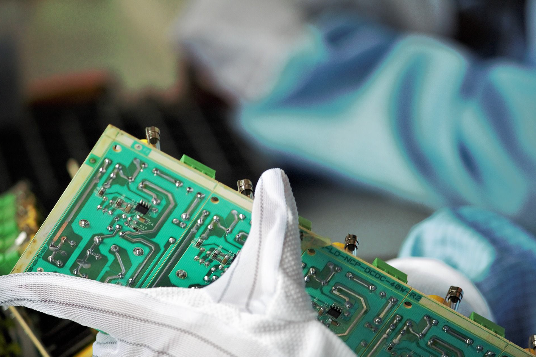 person wearing gloves and inspecting a semiconductor