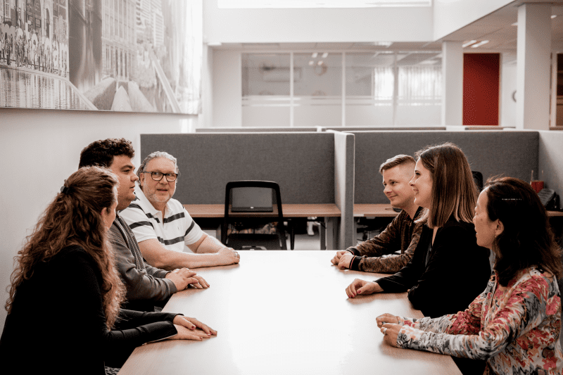 Six cheerful looking people having a discussion at a conference table.